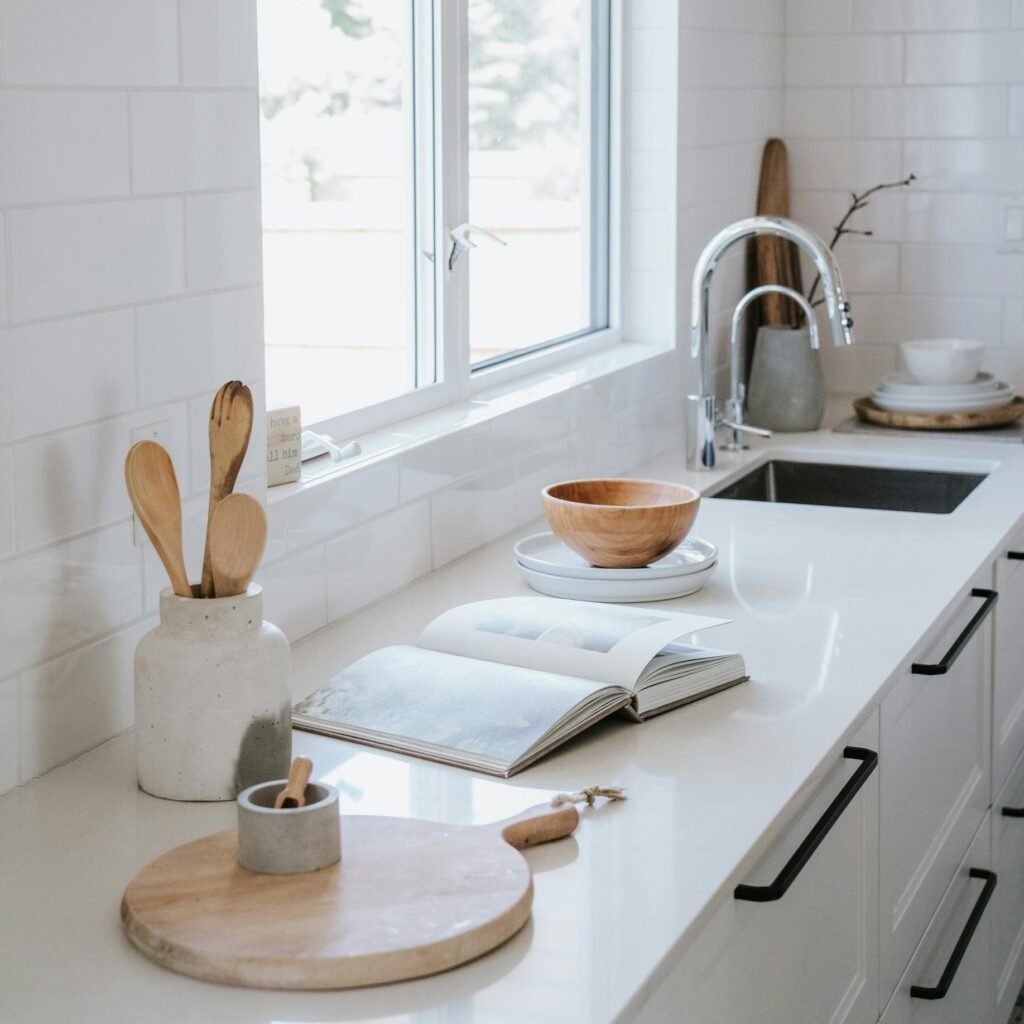 Serene japandi style kitchen featuring wooden utensils, faucet, and bright window.